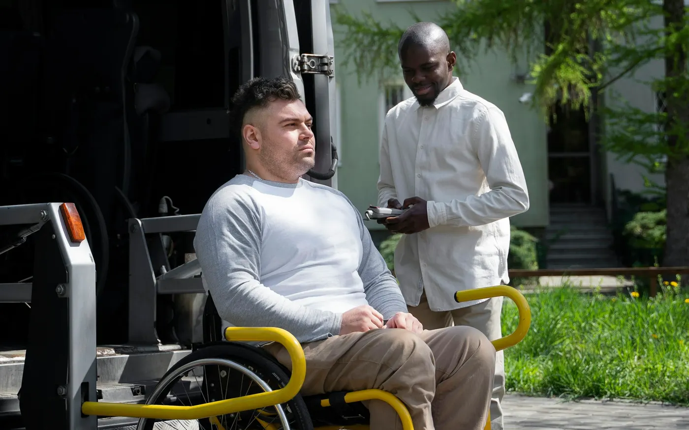 Usager en fauteuil roulant devant une camionnette de transport adapté