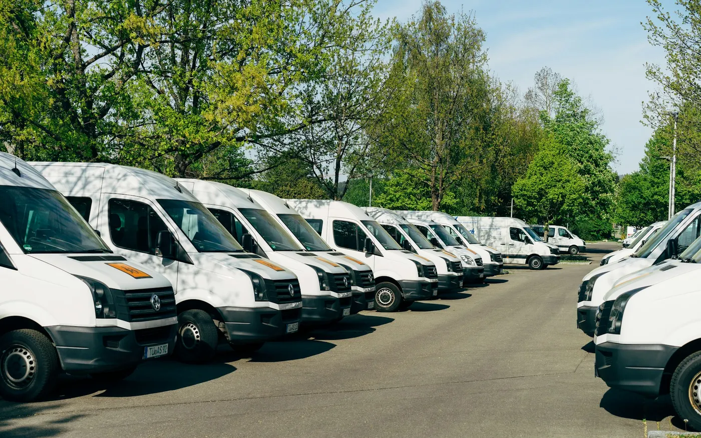 Fourgons de transport adapté stationnés sur le parking d'un établissement avant le départ des tournées