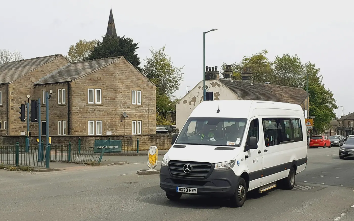 Minibus blanc de transport adapté circulant en ville pendant une tournée de ramassage